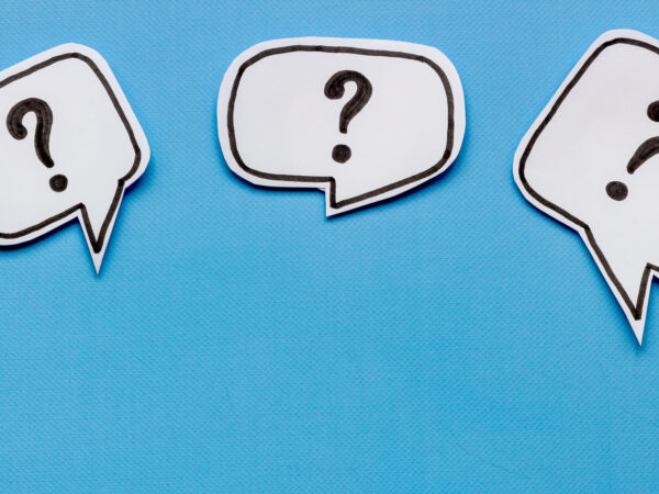A photo of three white paper speech bubbles on a blue background. The speech bubbles are on a light blue background.