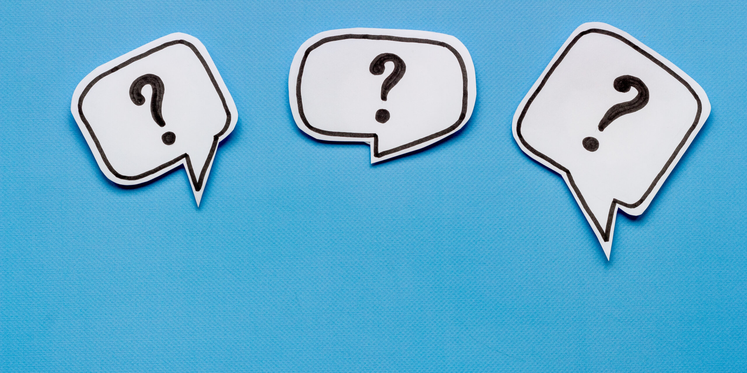 A photo of three white paper speech bubbles on a blue background. The speech bubbles are on a light blue background.